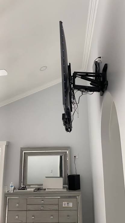Handyman mounting a TV with a power drill